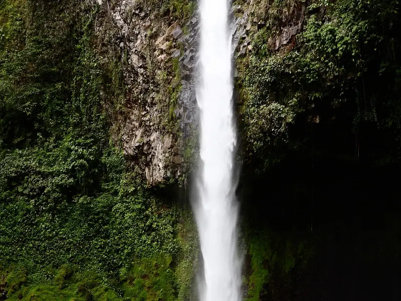 Hoge waterval die langs een begroeide rotswand omlaag valt in Rincón de la Vieja
