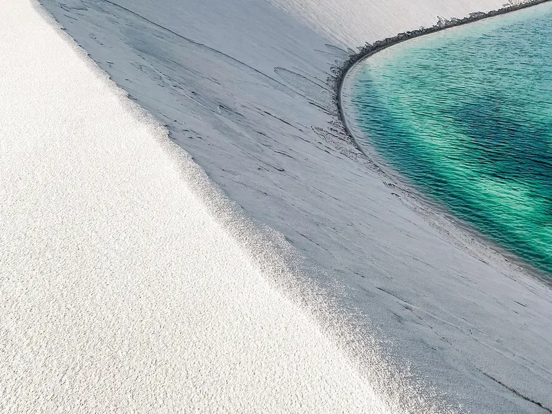 Licht zand dat in een boog langs turquoise water loopt in Marino Ballena National Park bij Uvita